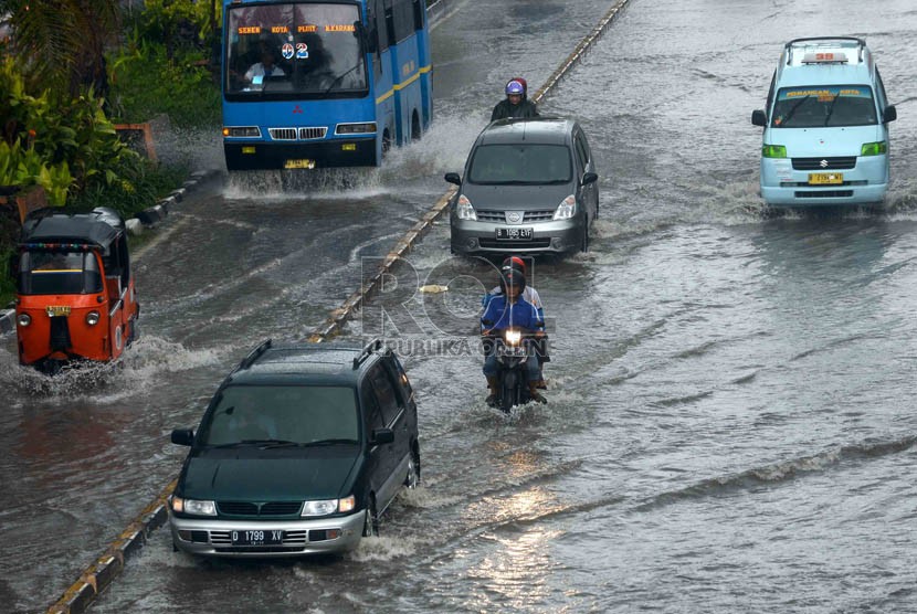 Pengendara nekad menerobos genangan air di Jalan Gunung Sahari, Jakarta, Ahad (12/1).  (Republika/Agung Supriyanto)