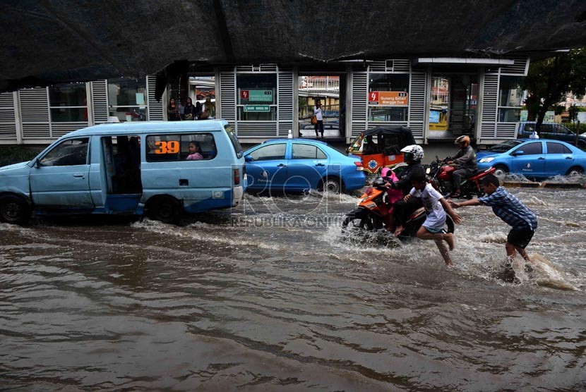 Pengendara nekad menerobos genangan air di Jalan Gunung Sahari, Jakarta, Ahad (12/1).  (Republika/Agung Supriyanto)