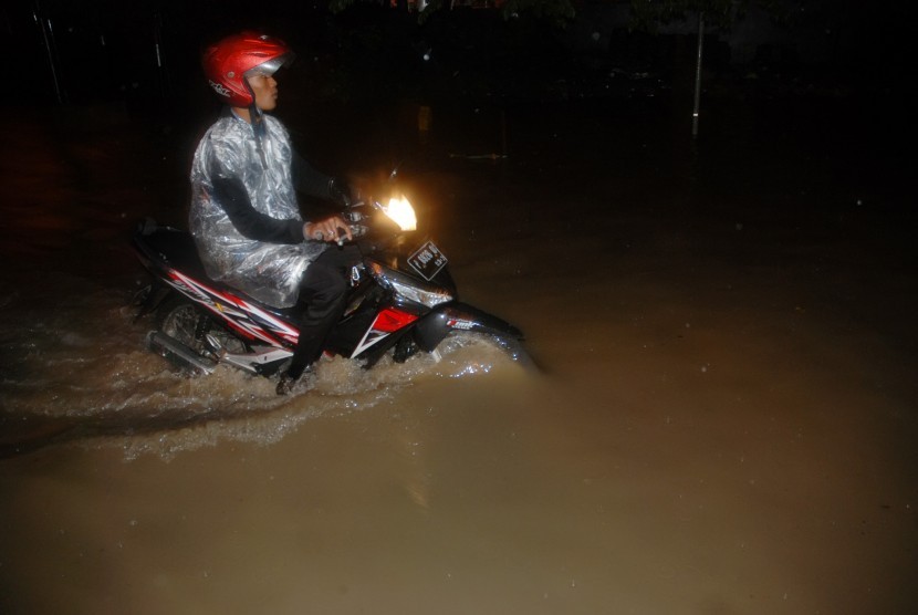 Pengendara roda dua berusaha melintasi banjir di Gedebage, Bandung, Jawa Barat, Jumat (28/10). 