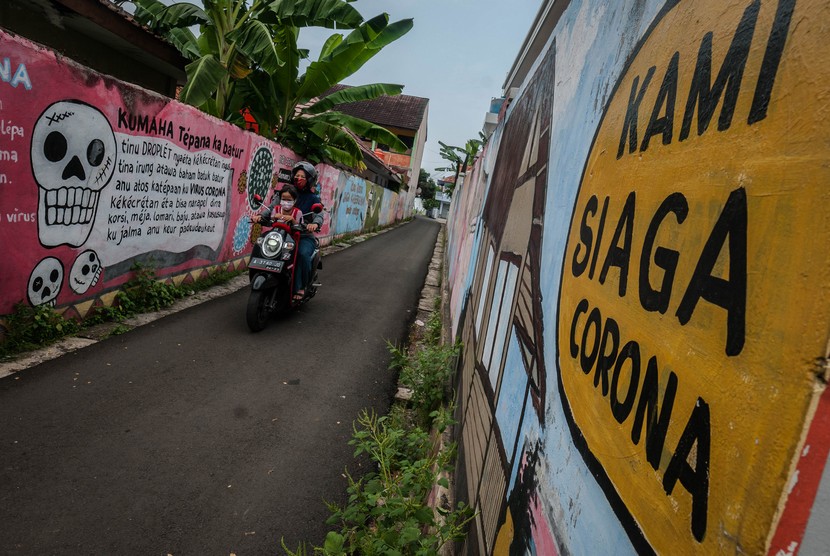 Pengendara roda dua melintas di depan mural informasi bahaya COVID-19 di Pandeglang, Banten, Selasa (31/8/2021). Ketua Bidang Perubahan Perilaku Satgas Penanganan COVID-19 Sonny Harry B Harmadi mengatakan Positivity Rate di Indonesia saat ini turun di angka 12,13 persen dibandingkan pada puncak kasus pada Minggu ketiga bulan Juli di angka 30,55 persen. 