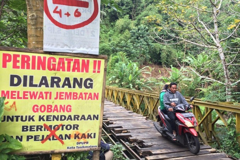 Pengendara roda dua memaksa melintas di Jembatan Gobang yang menghubungkan Kecamatan Purbaratu Kota Tasikmalaya dengan Kecamatan Manonjaya Kabupaten Tasikmalaya, Juma (14/6). 