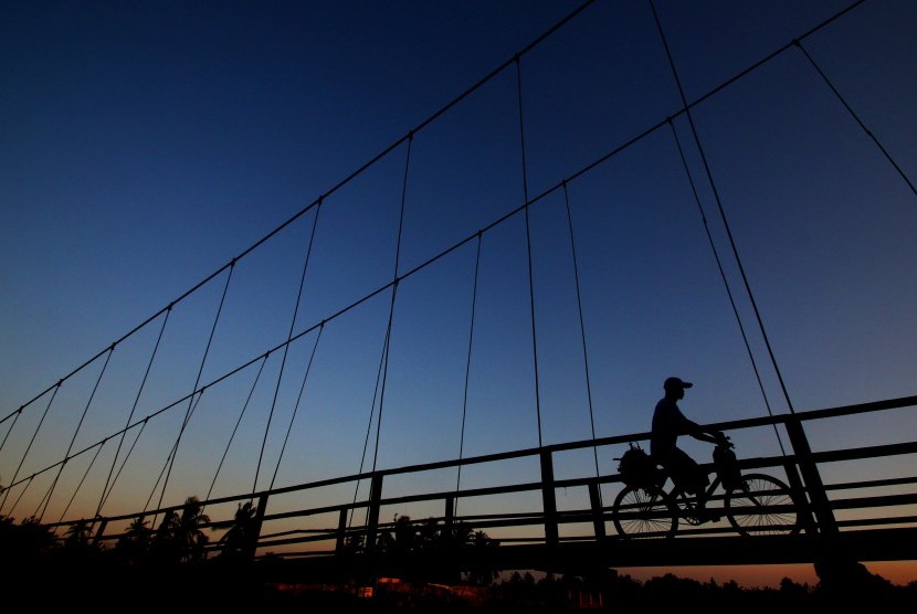 Pengendara sepeda melintasi Jembatan Gantung Muara Gembong, Bekasi, Jawa Barat, Kamis (8/6). Jembatan itu menjadi satu-satunya sarana penyeberangan antardesa yang terkena dampak abrasi di Kecamatan Muara Gembong. (Ilustrasi)