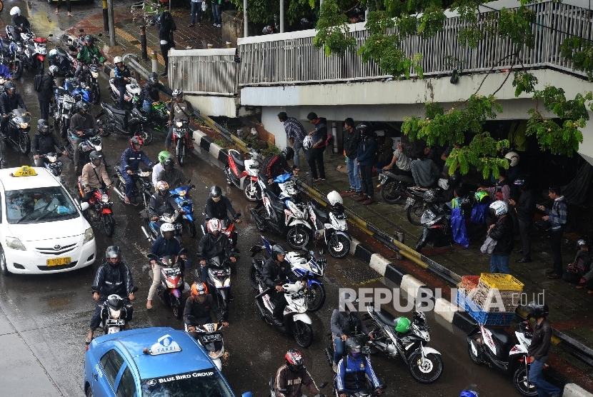  Pengendara sepeda motor dengan menggunakan jas hujan menerobos hujan di Kawasan Salemba, Jakarta, Senin (5/12).