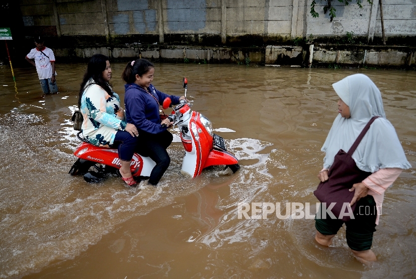 Pengendara sepeda motor berusaha melintasi banjir di Kawasan Bukit Duri, Jakarta, Rabu (8/3).