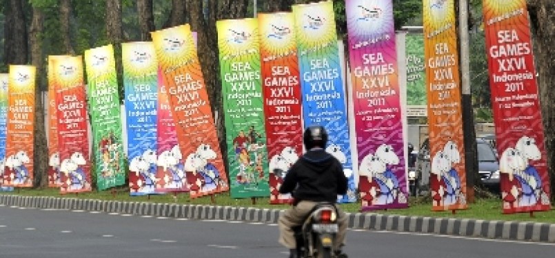Pengendara sepeda motor melaju di samping deretan banner sosialisasi perhelatan pesta olahraga negara-negara Asean, SEA Games ke-26 Indonesia di Jakarta.