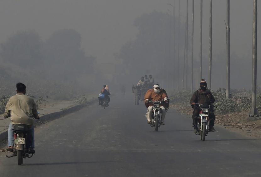 Pengendara sepeda motor melaju di sepanjang jalan saat kabut asap menyelimuti kawasan Lahore, Pakistan, Senin, 22 November 2021. Warga Lahore dan sekitarnya menderita gangguan pernapasan akibat kualitas udara yang buruk terkait kabut asap tebal yang menyelimuti kawasan tersebut.
