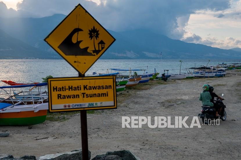 Pengendara sepeda motor melintas di dekat tambatan perahu di Pantai Teluk Palu, Sulawesi Tengah, Senin (26/4/2021). Pemerintah dan sejumlah Lembaga Swadaya Masyarakat (LSM) melakukan mitigasi bencana dengan memasang papan peringatan kawasan rawan tsunami di sejumlah titik di pantai yang telah diterjang lima kali tsunami sejak tahun 1908 itu.