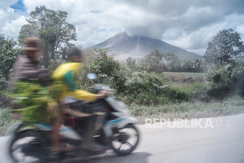 Pengendara sepeda motor melintas di jalan yang dipenuhi debu vulkanis erupsi Gunung Sinabung. (ilustrasi)