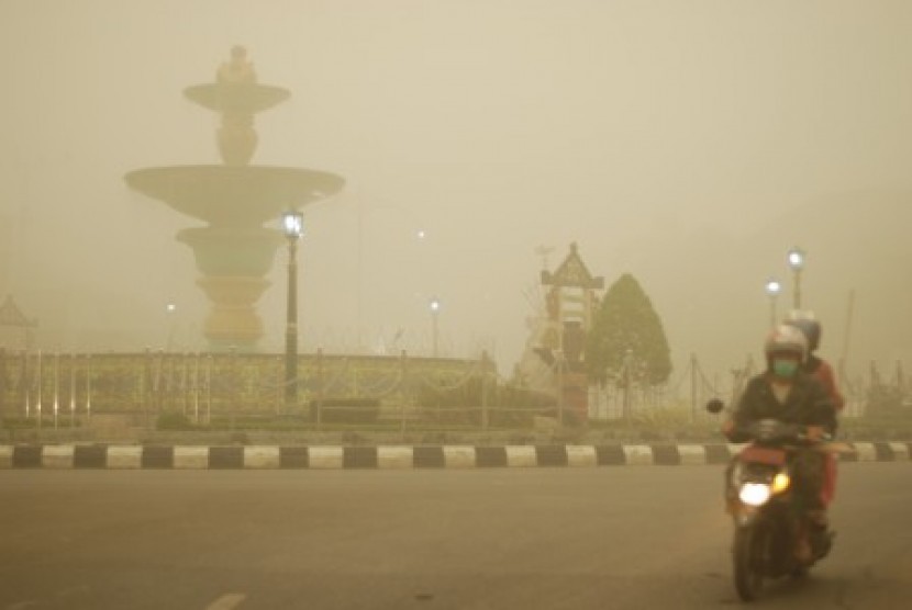 Pengendara sepeda motor melintas di kawasan Bundaran Air Mancur yang tertutup kabut asap tebal di Muara Teweh, Kabupaten Barito Utara, Kalimantan Tengah, Kamis (22/10).