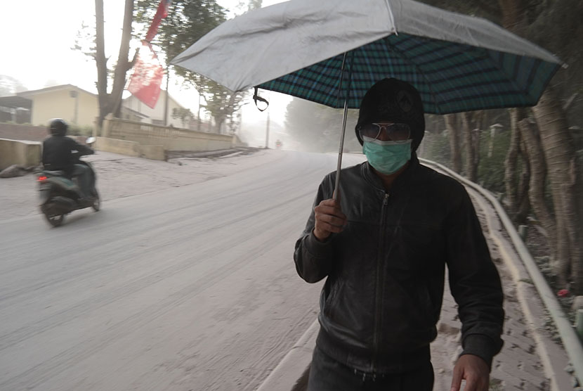 Warga melintas di jalan ketika hujan abu vulkanik erupsi Gunung Sinabung, di Berastagi, Karo, Sumatera Utara, Jumat (26/6).   (Antara/Irsan Mulyadi)