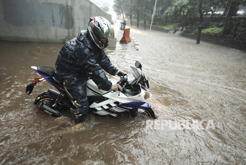 Pengendara sepeda motor melintasi banjir yang menggenangi kawasan Semanggi di Jakarta, Senin (11/12).