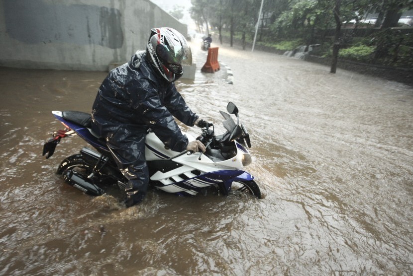 Pengendara sepeda motor melintasi banjir yang menggenangi kawasan Semanggi di Jakarta, Senin (11/12). Hujan deras disertai angin menyebabkan beberapa ruas jalan tergenang air.