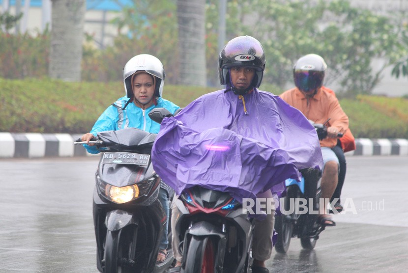 Pengendara sepeda motor melintasi Jalan Rahadi Oesman yang basah setelah hujan turun, di Pontianak, Kalimantan Barat, Senin (23/9/2019). 