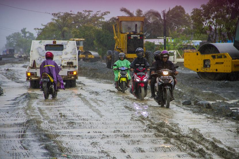 Pengendara sepeda motor melintasi Jalan Trans Kalimantan yang rusak. ilustrasi