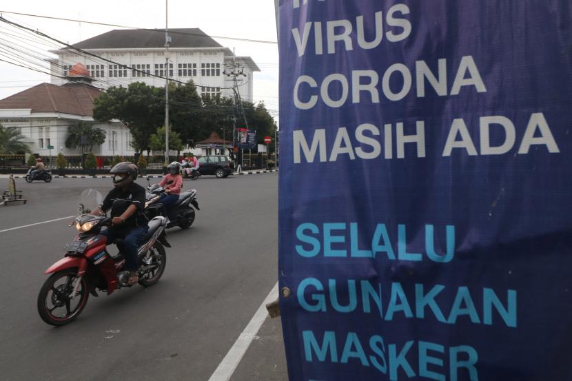Pengendara sepeda motor melintasi spanduk sosialisasi penerapan protokol kesehatan di Kota Kediri, Jawa Timur, Jumat (25/12/2020). Kedisiplinan masyarakat menerapkan protokol kesehatan di wilayah tersebut masih kurang meskipun pemerintah telah berupaya mensosialisasikan penanggulangan penyebaran COVID-19.