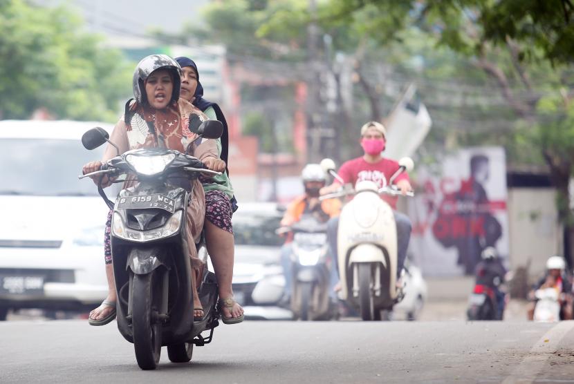 Pengendara sepeda motor memakai sandal jepit melintas di Jalan Raya Ciledug, Kreo, Tangerang, Banten.