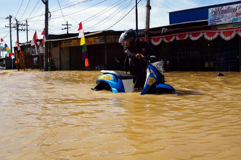 Pengendara sepeda motor menerobos banjir di Jalan Basuki Rahmat Kota Sorong, Papua Barat, Selasa (23/8/2022). 