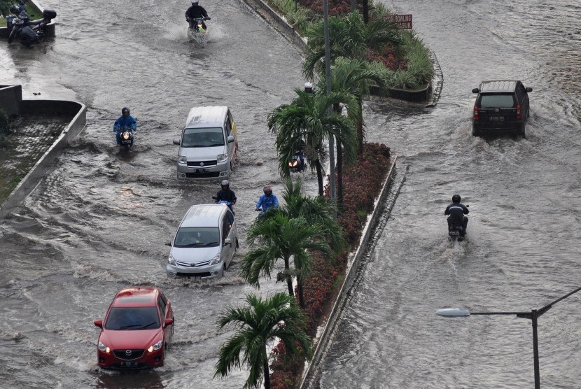 Pengendara sepeda motor menerobos banjir di jalan raya Lodan, Ancol, Jakarta Utara, Kamis (21/4). 