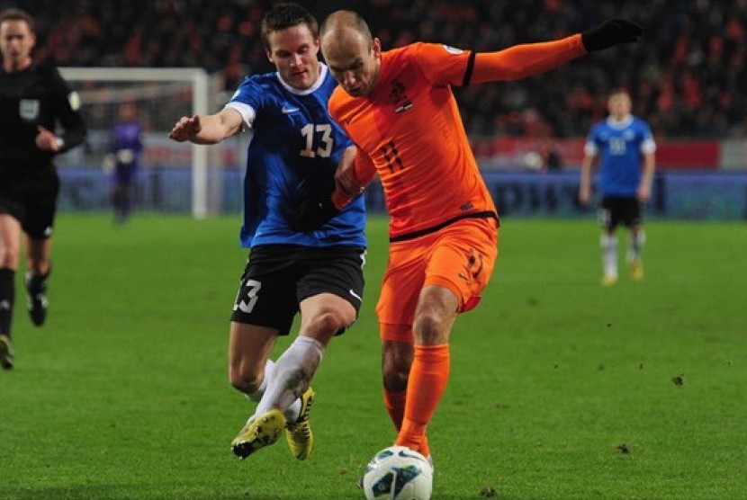 Penggawa timnas Estonia, Martin Vunk berebut bola dengan Arjen Robben.