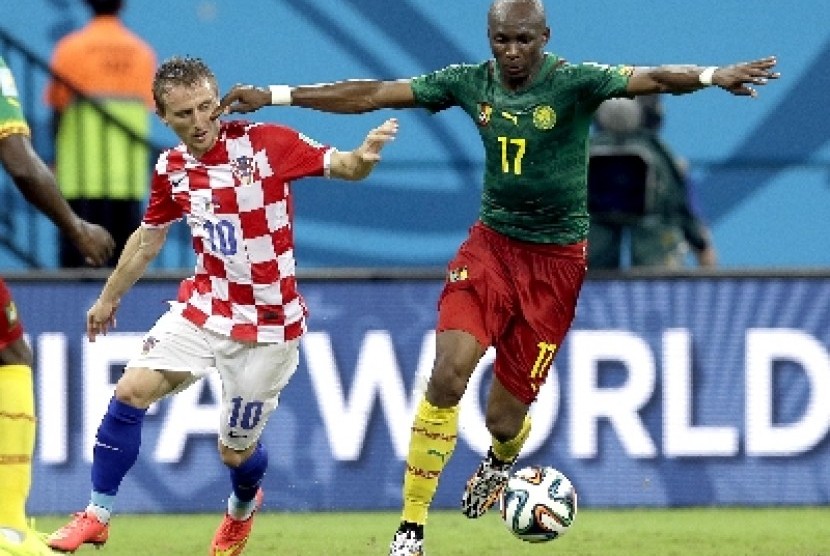 Penggawa timnas Kamerun Stephane Mbia berebut bola dengan gelandang timnas Kroasia, Luka Modric.