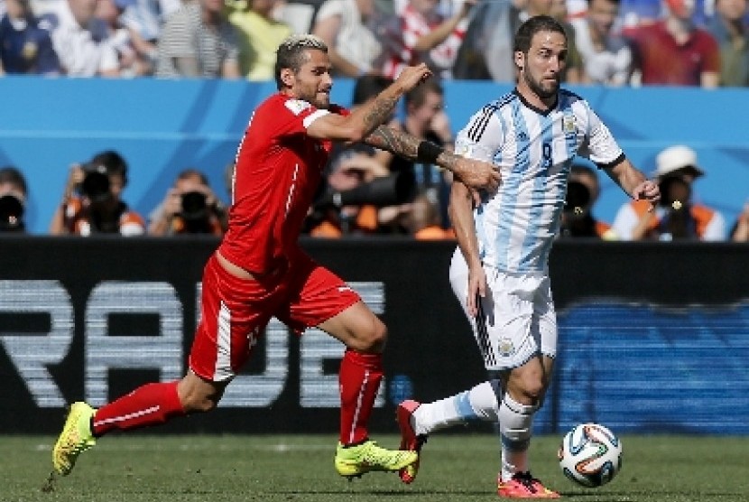 Penggawa timnas Swiss, Valon Behrami berebut bola dengan penyerang timnas Argentina, Gonzalo Higuain di Piala Dunia 2014.