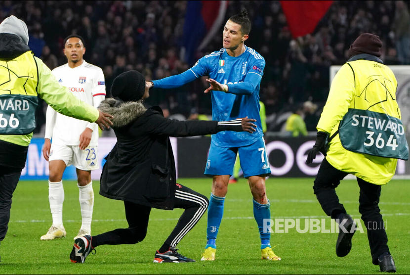 Penggemar Cristiano Ronaldo menyerbu ke lapangan pada leg pertama babak 16 besar Liga Champions antara Lyon dan Juventus di Lyon, Prancis, Kamis (27/2). 