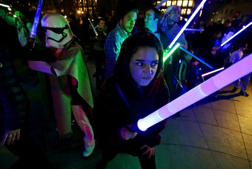 Penggemar film Star Wars bermain dengan senjata lightsaber khas dari film tersebut.