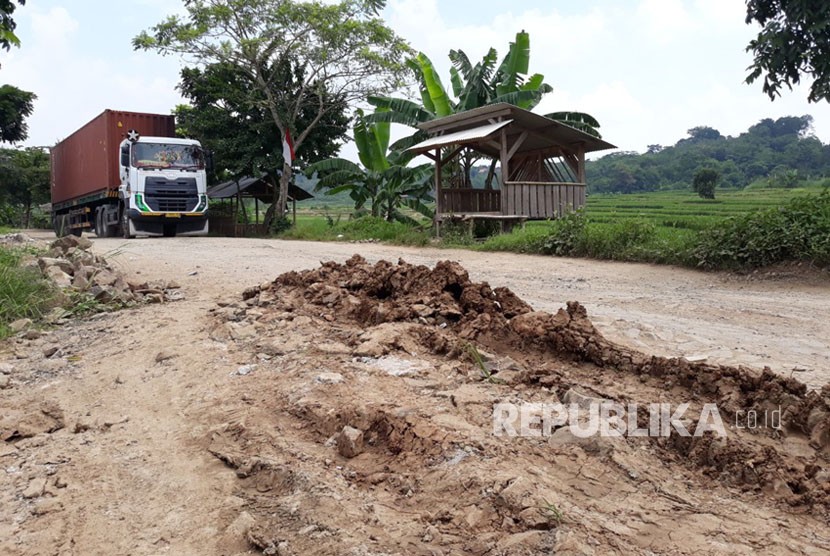 Pengguna jalan dan kontainer melintasi jalan lingkar barat KM 0 yang kondisinya rusak parah, di Kampung Cikadu, Desa Kadu Mekar, Kecamatan Babakan Cikao, Purwakarta, Rabu (14/3). 