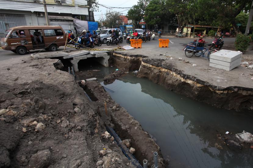 Pengguna jalan melintas di dekat pengerjaan saluran air di Jalan Tambaksari, Surabaya, Jawa Timur. Pemkot Surabaya melakukan pembangunan saluran-saluran air di sejumlah lokasi untuk mengantisipasi banjir saat musim hujan. 