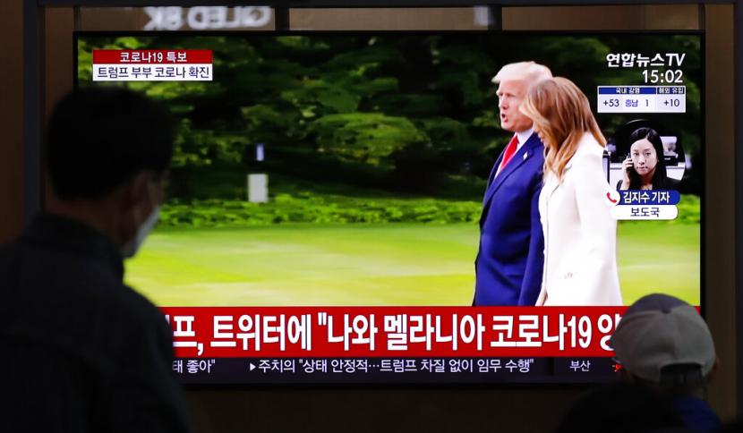 Pengguna kereta di Seoul, Korsel, berhenti sejenak menyimak berita Presiden AS Donald Trump dan istrinya Melania yang dites positif Covid-19, Jumat (2/10).
