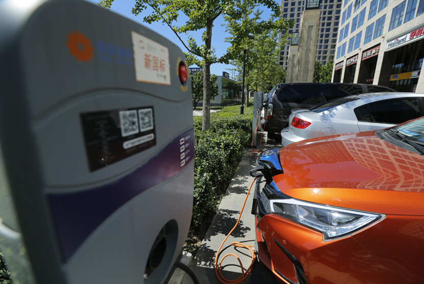 Pengisian kendaraan mobil berbahan bakar listrik di luar sebuah apartemen di Beijing, China.  Penjualan kendaraan berbahan bakar minyak akan dilarang mulai 2030 di Hainan. Ilustrasi.
