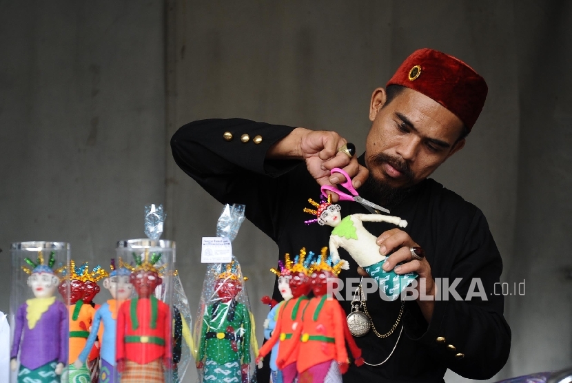  Pengrajin menyelesaikan pembuatan boneka ondel-ondel saat di gelar bazar UMKM di stasiun Gambir, Jakarta, Rabu (28\12). 