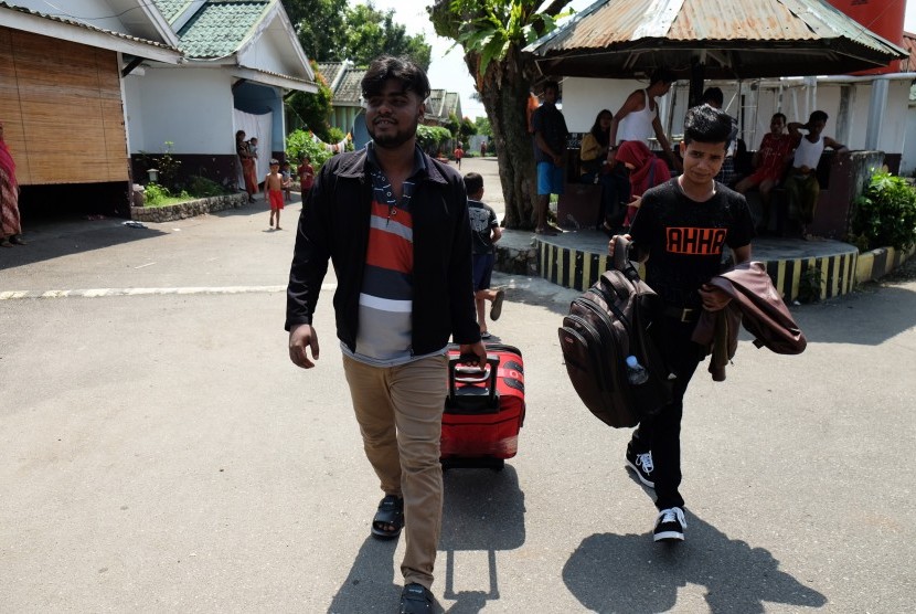 Pengungsi etnis Rohingya, Myanmar Hasan Ali (kanan) dibantu rekannya sesama pengungsi membawa barang-barangnya saat akan berangkat ke bandara untuk diterbangkan ke Amerika Serikat di lokasi penampungan, Medan, Sumatera Utara, Rabu (19/6/2019). 