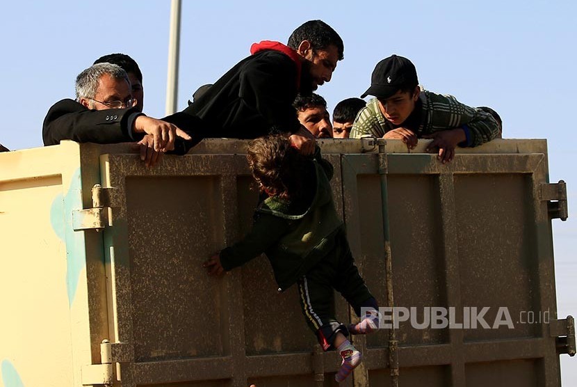 Pengungsi Irak di Mosul menarik lengan anaknya menaiki truk yang akan mengangkut mereka.