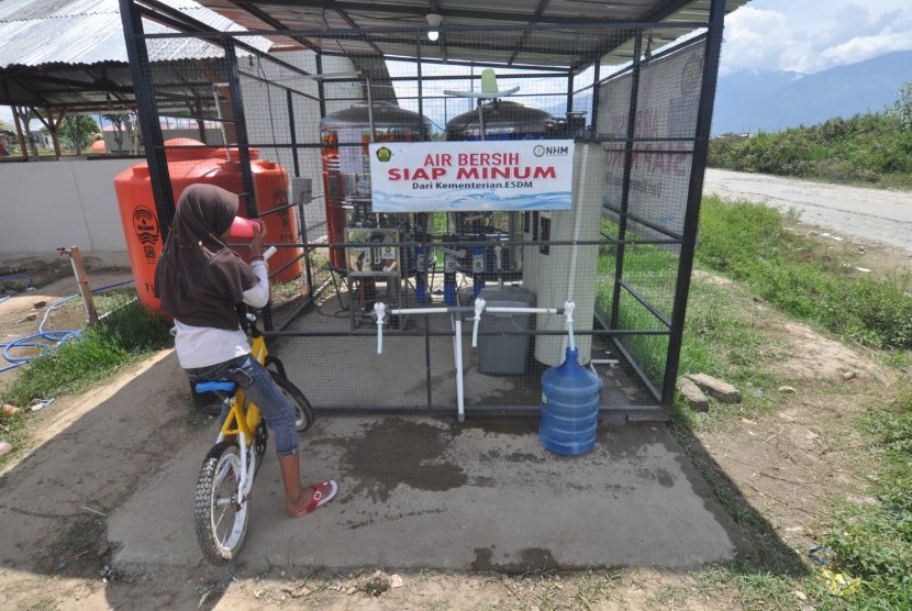 Pengungsi korban gempa dan likuifaksi mengisi air ke dalam galon dan meminum air siap minum yang disediakan secara gratis di Lokasi Pengungsian di Desa Lolu, Kabupaten Sigi, Sulawesi Tengah, Jumat (30/11/2018). 