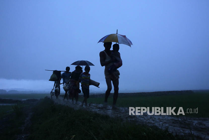 Pengungsi Rohingya berjalan di bawah hujan saat mereka tiba di perbatasan Bangladesh di Teknaf, Bangladesh, Sabtu (9/9).