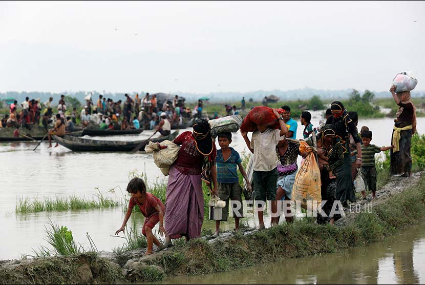 Pengungsi Rohingya berjalan di jalan berlumpur di pesawahan setelah melintasi perbatasan Bangladesh-Myanmar di Teknaf, Bangladesh, Rabu (6/9).
