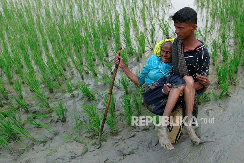 Pengungsi Rohingya dibopong melintasi pesawahan setelah melintasi perbatasan Bangladesh-Myanmar di Teknaf, Bangladesh, Rabu (6/9).