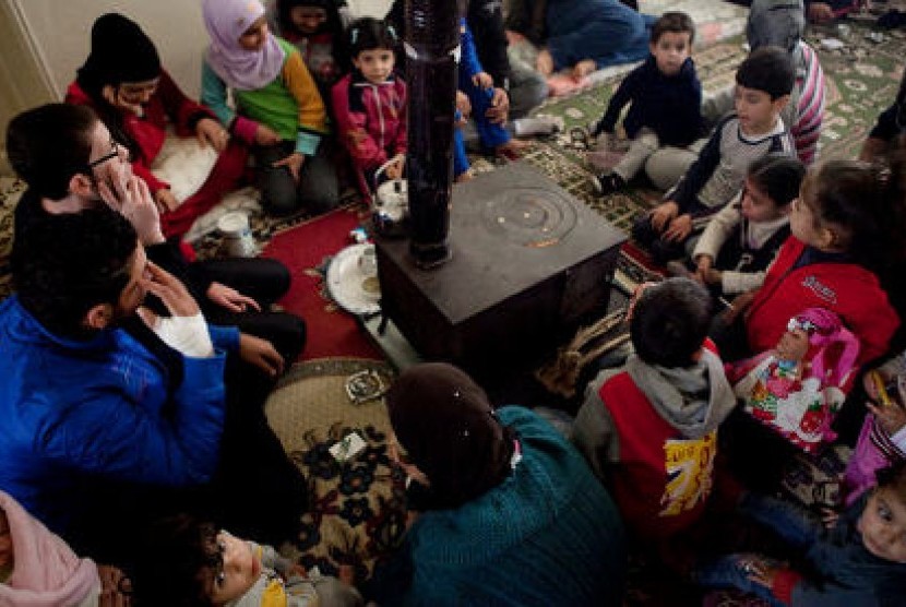 Pengungsi Suriah di Lebanon mengelilingi tungku untuk menghangatkan diri.