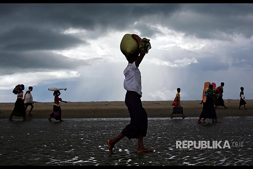 Pengungusi Rohingya berjalan di pesisir Teluk Bengal, di Shah Porir Dwip, Bangladesh, Selasa (11/9)