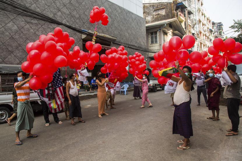  Pengunjuk rasa anti-kudeta memegang balon merah yang ditempeli selebaran dengan berbagai pesan sebelum dilepaskan ke langit saat pertemuan Rabu, 24 Maret 2021 di Yangon, Myanmar. 