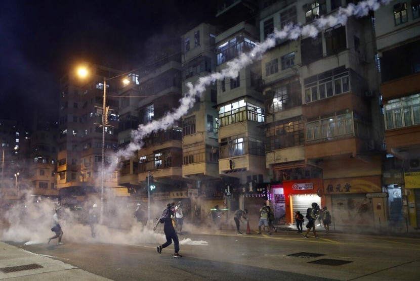 Pengunjuk rasa bereaksi terhadap gas air mata dari kantor polisi Shum Shui Po di Hong Kong, Rabu (14/8).