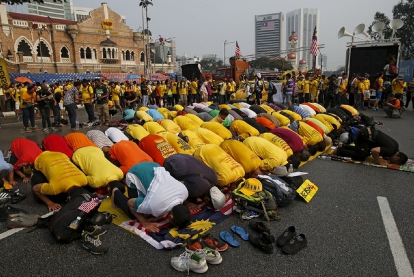 Pengunjuk rasa berkaus kuning menjalankan shalat di Dataran Merdeka, Ahad (30/8). Mereka berunjuk rasa menuntut pengunduran diri PM Malaysia, Najib Razak, yang terlilit dugaan korupsi.