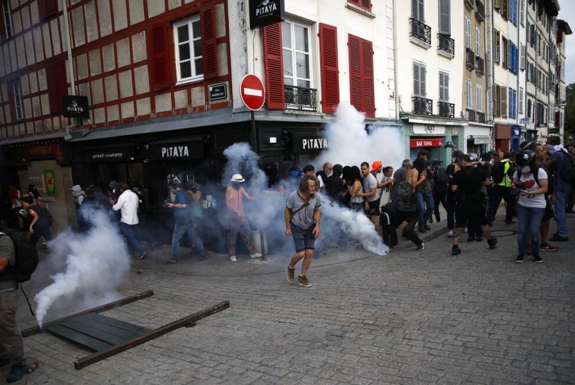 Pengunjuk rasa lari dari tembakan gas air mata oleh polisi di Bayonne, Prancis, Ahad (25/8). Pengunjuk rasa ada di Bayonne dalam rangka KTT G7 yang dihelat di Biarritz. 