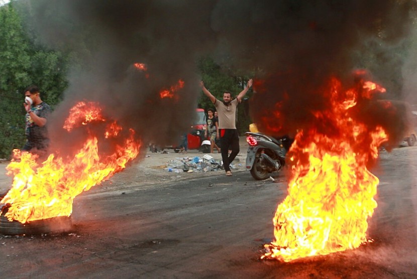 Pengunjuk rasa melakukan pembakaran dan memblokir jalan selama demonstrasi di Baghdad, Irak, Ahad (6/10). Lebih dari 100 orang meninggal dalam protes tersebut.
