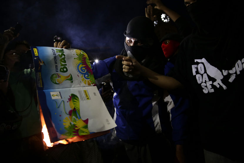   Pengunjuk rasa membakar majalah FIFA WOrld Cup saat memprotes Piala Dunia di Rio de Janeiro, Brasil, Kamis (15/5).