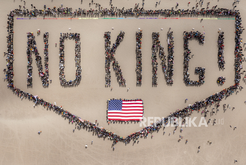 Pengunjuk rasa membentuk spanduk manusia di Pantai Ocean saat aksi protes No Kings di San Francisco pada Sabtu, 14 Juni 2025. 