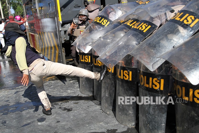 Pengunjuk rasa menendang barikade personel Polda Sulawesi Tenggara saat aksi menuntut penuntasan kasus kematian mahasiswa di depan Polda Sulawesi Tenggara, Kendari, Sulawesi Tenggara, Selasa (22/10/2019). 