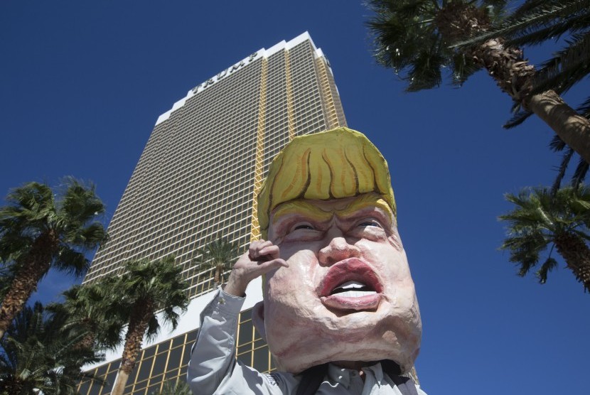 Pengunjuk rasa mengenakan kostum Donald Trump di luar hotel milik Trump di Las Vegas, Amerika.