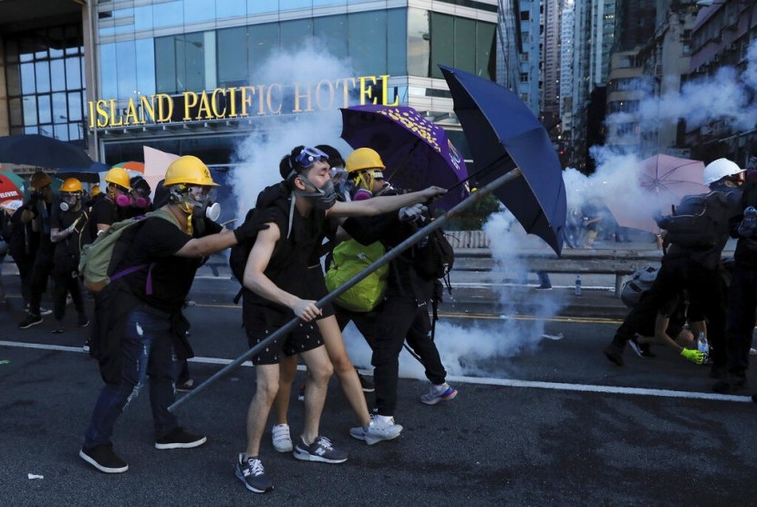 Pengunjuk rasa menggunakan payung untuk melindungi diri dari gas air mata di Hong Kong, Ahad (28/7).